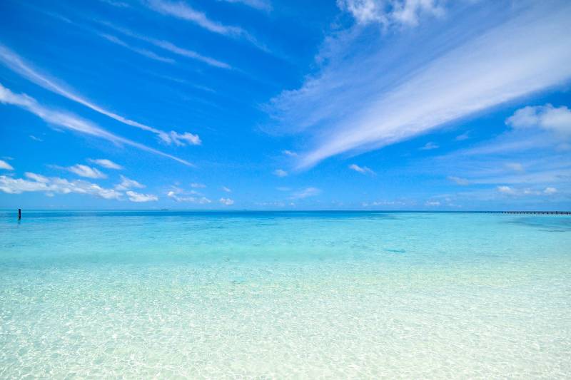 Exotischer Strandabschnitt mit weißem Sand, türkisfarbenen Wasser und blauem Himmel