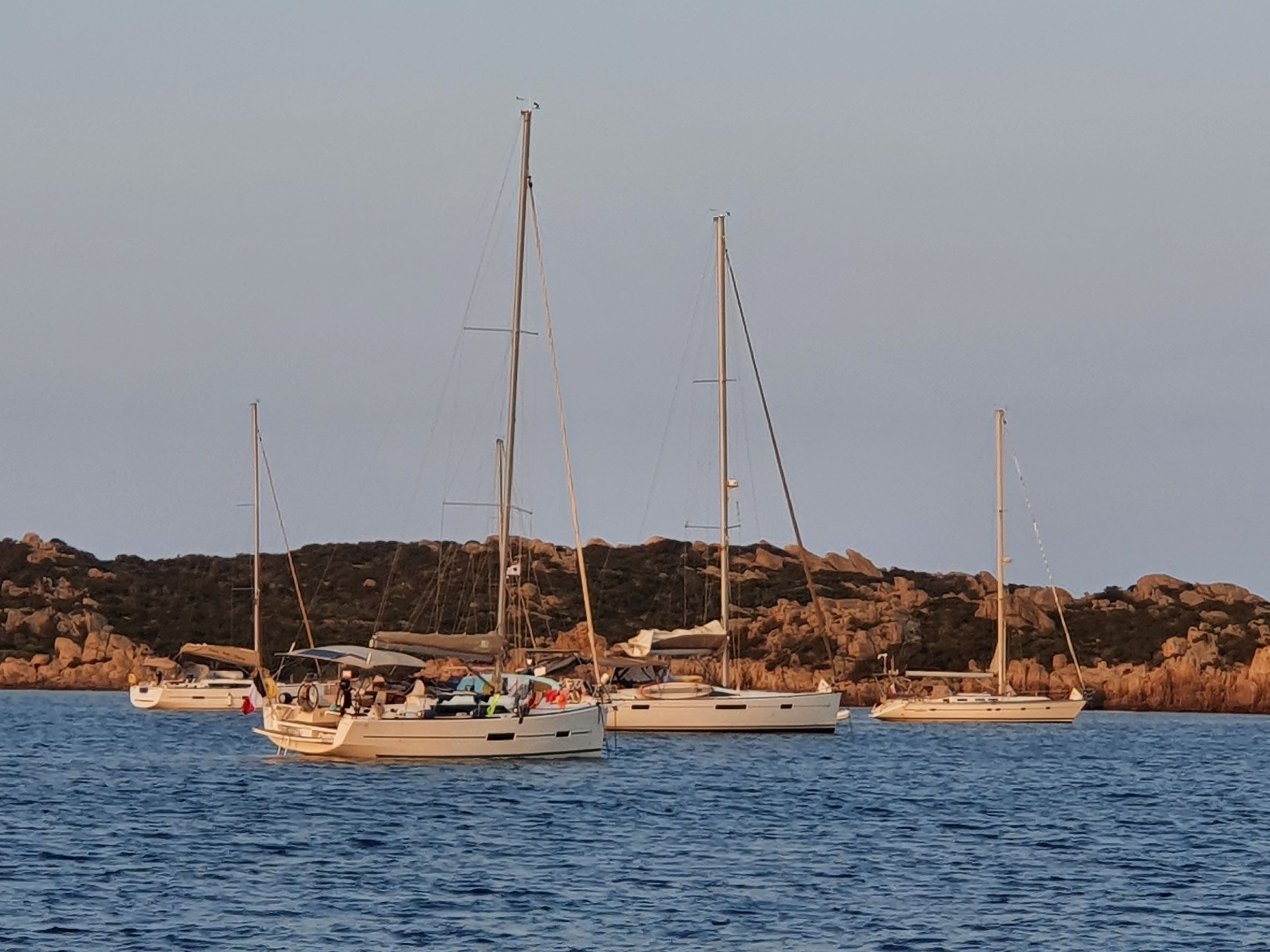 Vier Yachten im Sonnenuntergang vor roten Felsen