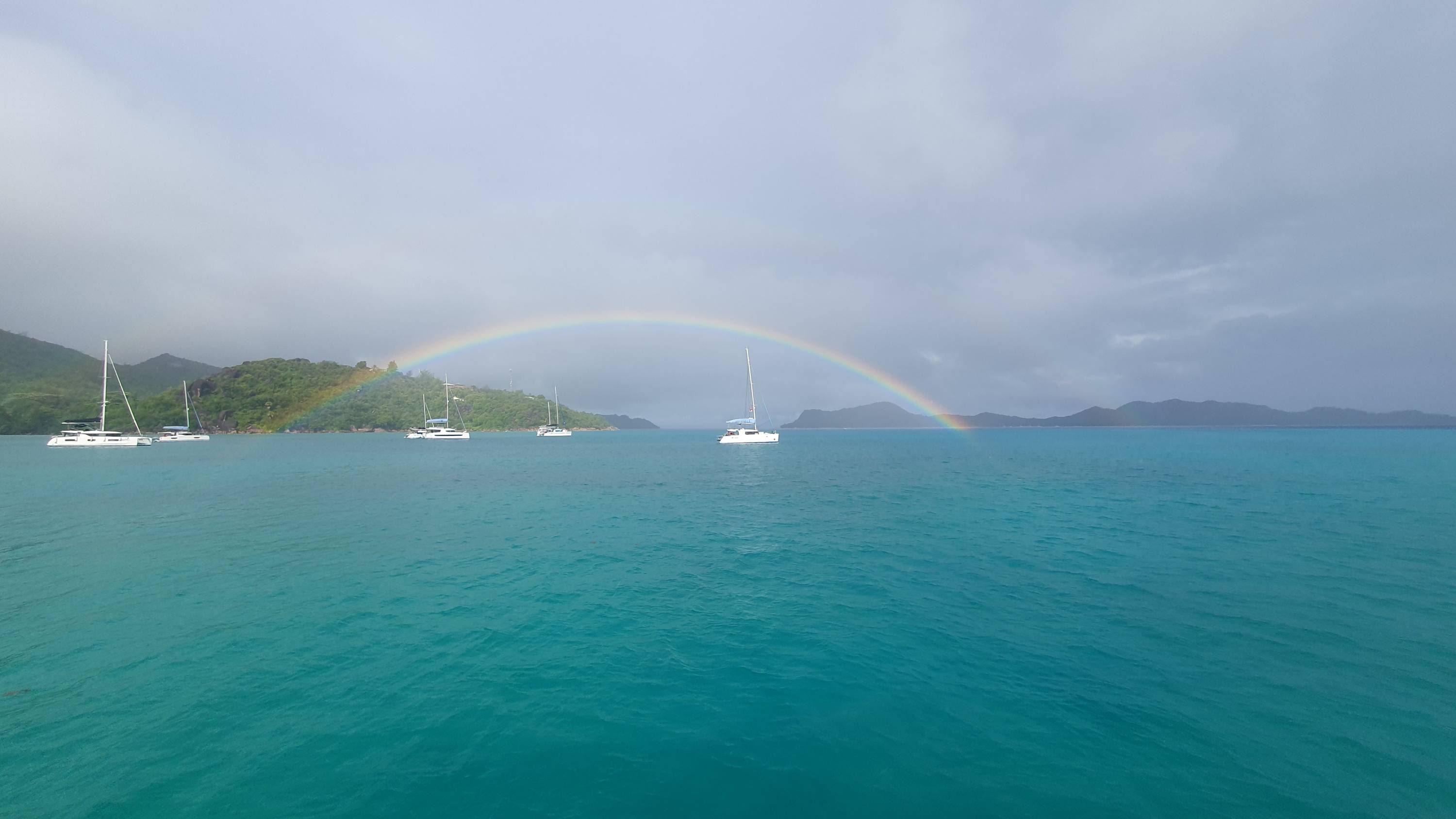 Ein ganzer Regenbogen über ankernden Schiffen