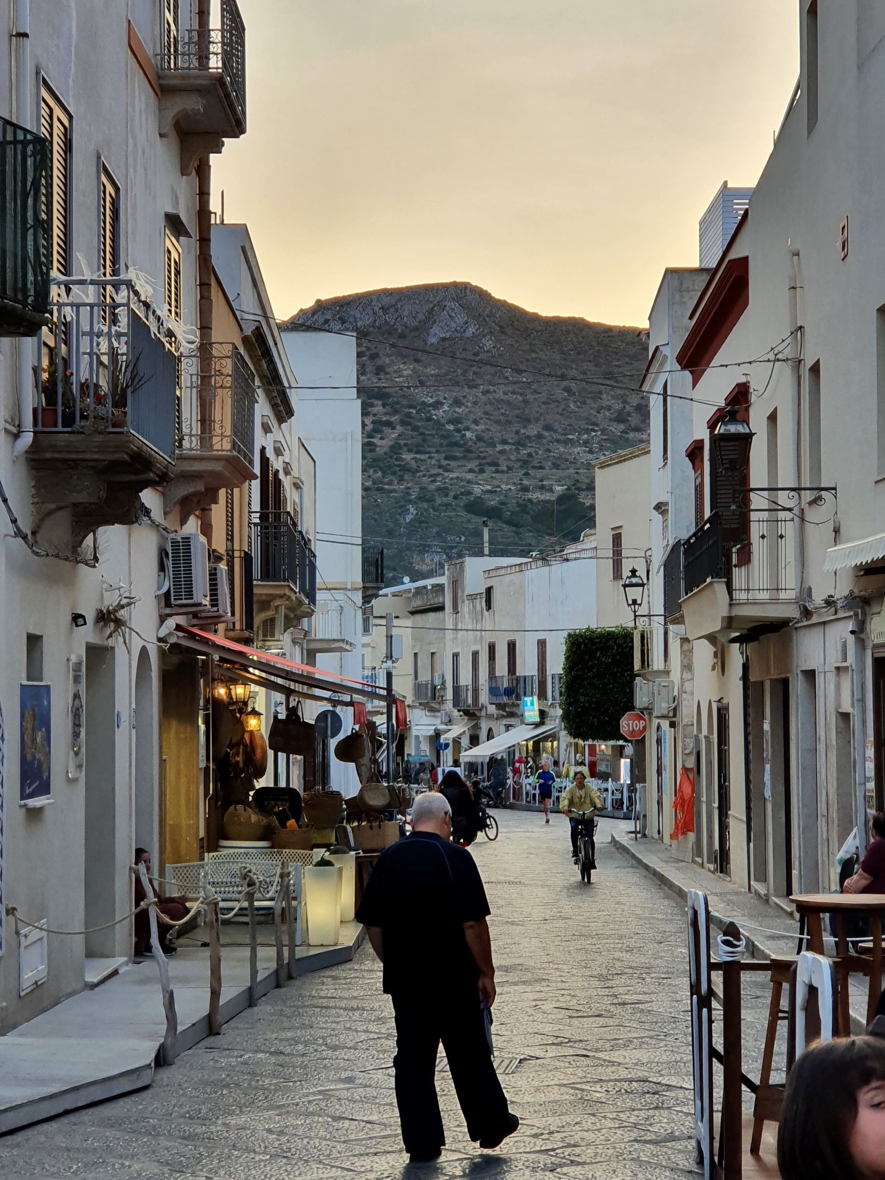 Gasse in italienischen Urlaubsdorf bei Sonnenuntergang mit Spaziergänger.