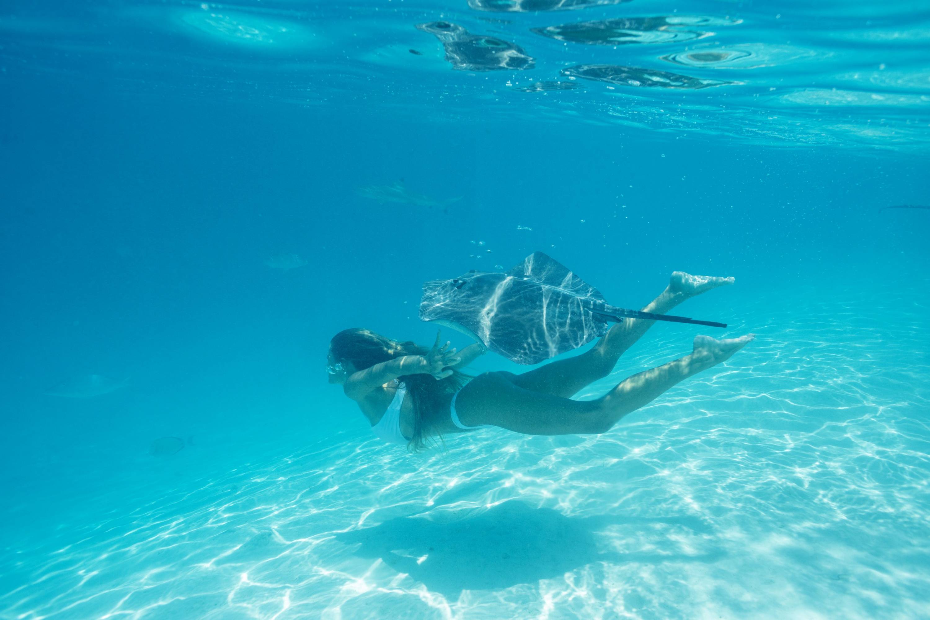 Frau schnorchelt im türkisblauen Wasser von Bora Bora neben einem Stachelrochen.