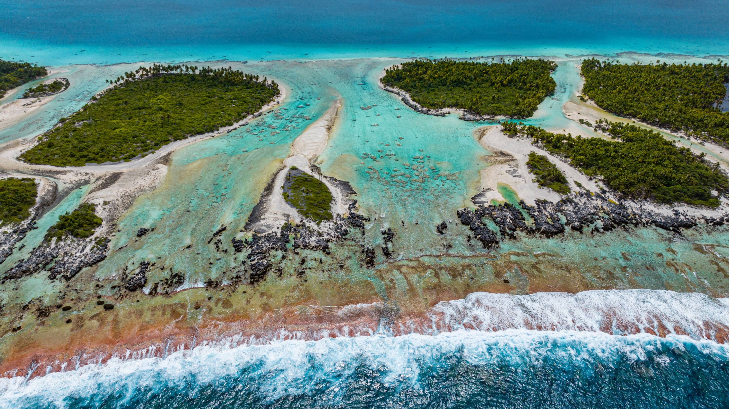 Luftaufnahme des Atolls von Rangiroa mit türkisfarbenen Lagunen, kleinen Inseln und Riffdurchbrüchen im Tuamotu-Archipel, Französisch-Polynesien.