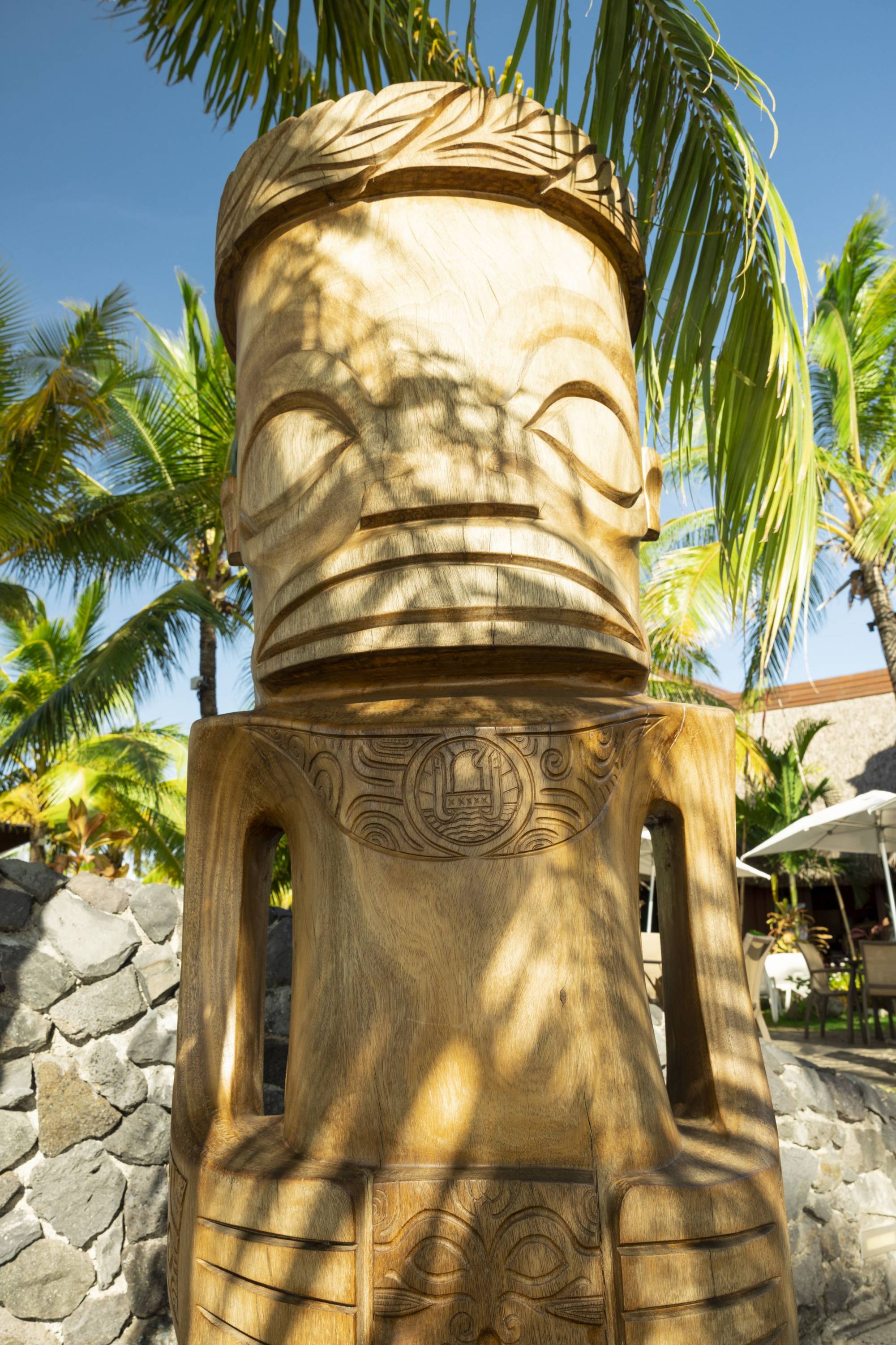 Große polynesische Holzskulptur mit traditionellen Schnitzmustern unter Palmen auf Tahiti.
