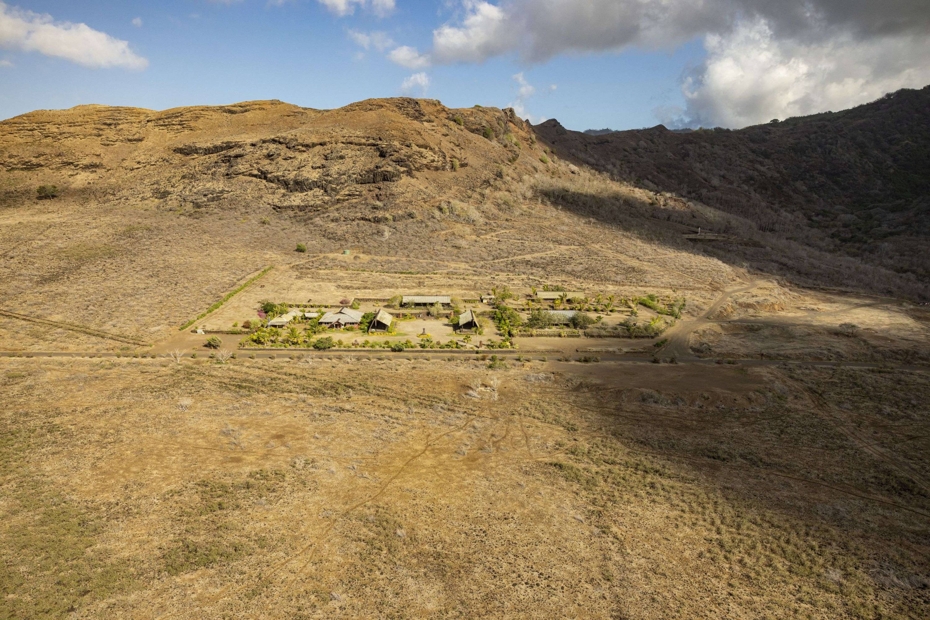 Luftaufnahme einer abgelegenen Anlage inmitten der trockenen, kargen Hügellandschaft von Ua Huka auf den Marquesas-Inseln.