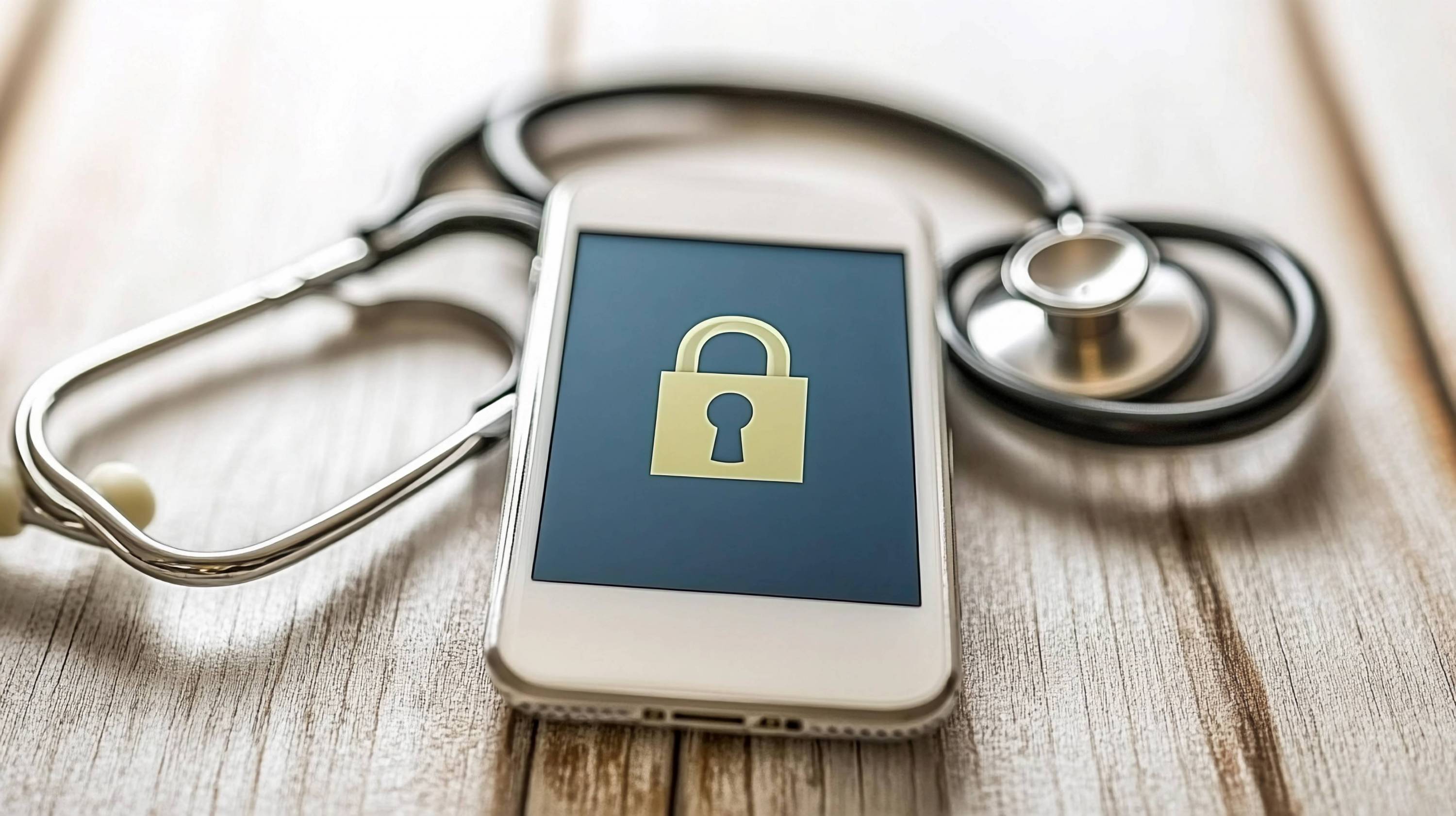 Ein Handy mit einem Schloß auf dem Bildschirm liegt auf einem Holzuntergrund Daneben ein Stetoskop.